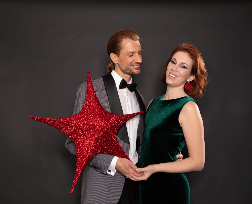 Verliebtes Paar mit Weihnachtsstern in Rot und Ohrringen von Romy North